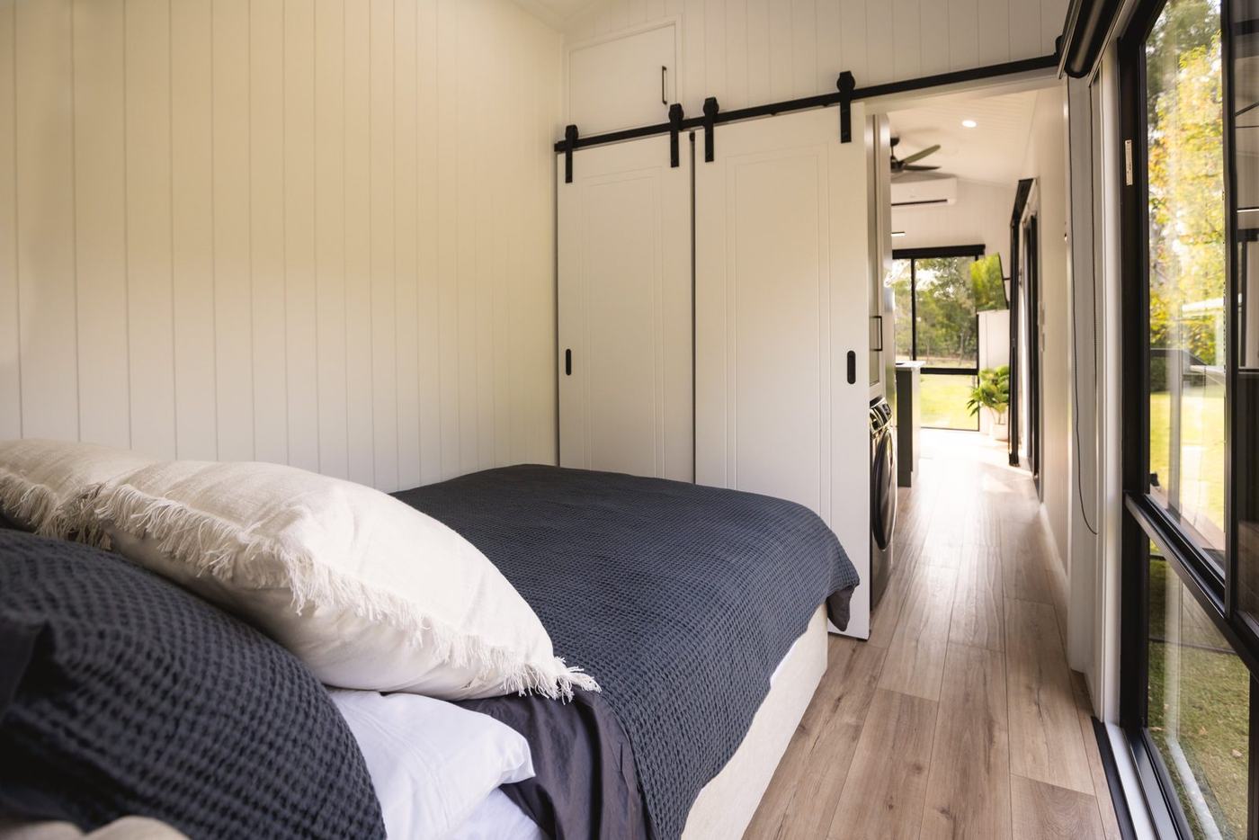 Bedroom of the Panarama with barn doors open to the hallway and kitchen
