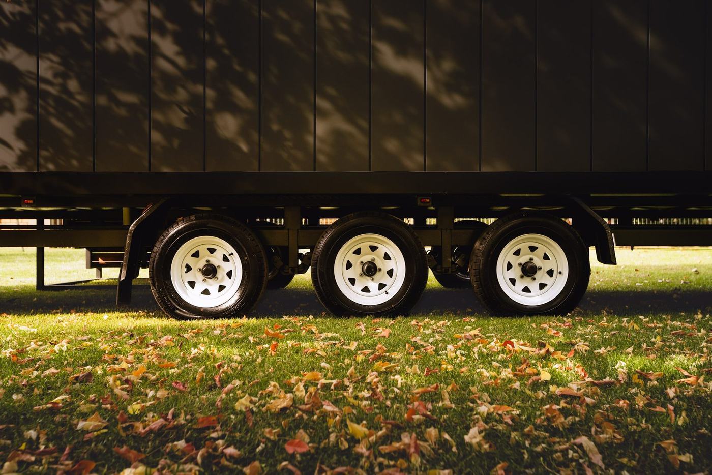Triple axle wheels of the Panarama tiny home on autumn leaves